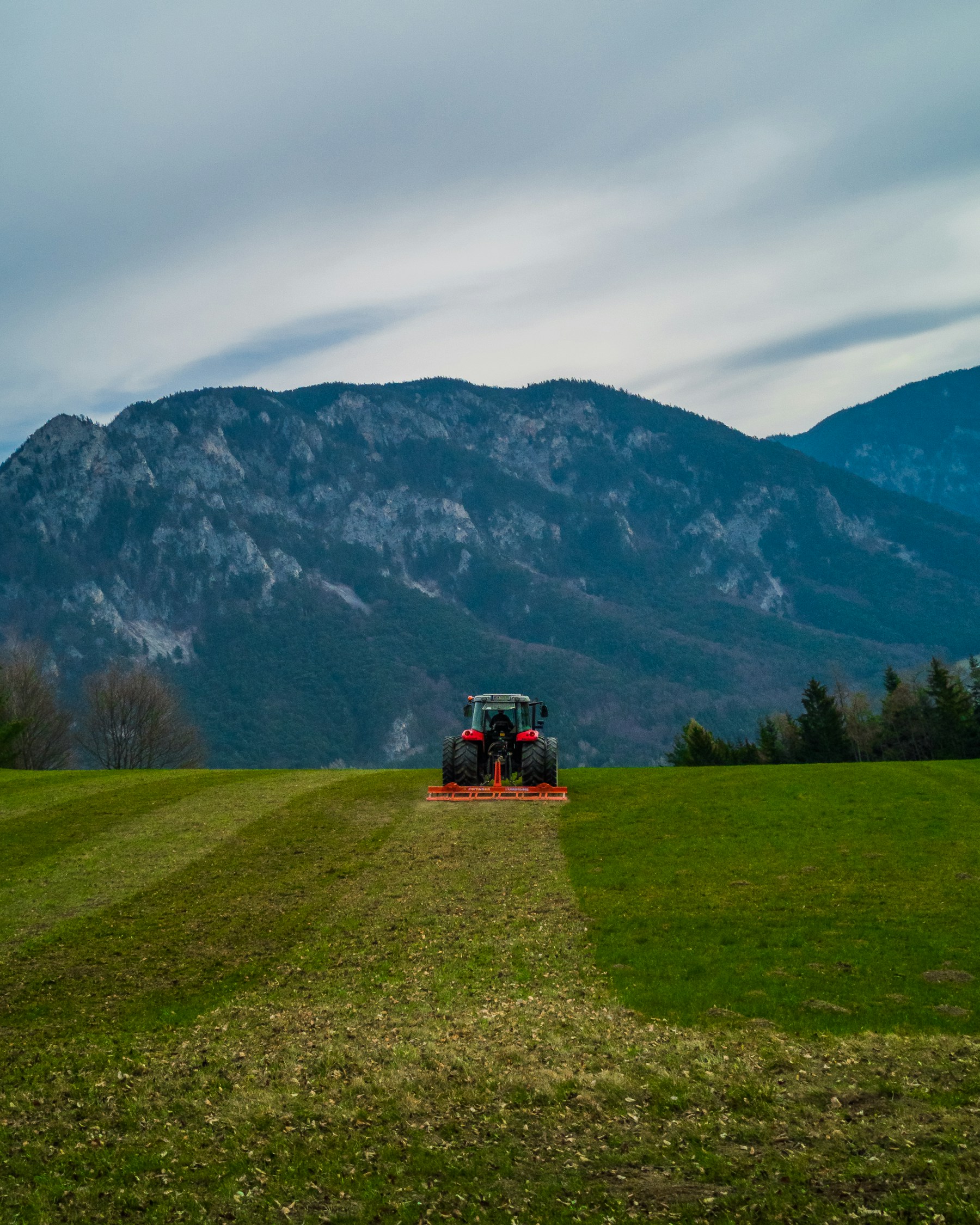 Traktor auf einer Wiese vor Bergen als Beispiel für landwirtschaftliche Flächen.